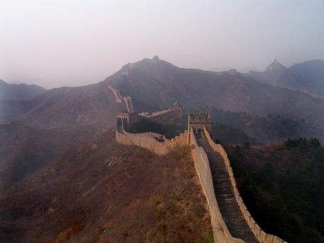 Scenic landscape view of the Great Wall of China stretching away across the mountain peaks into the mist in the distance