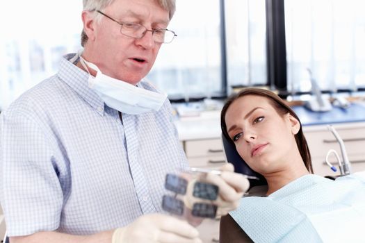 Doctor showing x-ray to female patient. Portrait of mature doctor showing dental x-ray to his female patient