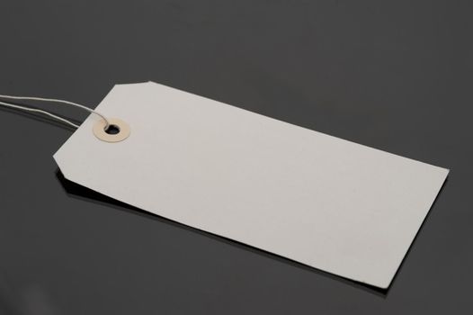 Close Up of Blank Luggage Tag with String on Dark Grey Background, Copy Space for Personalization