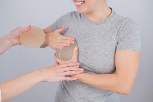 Caucasian woman trying on breast implants. A plastic surgeon helps a patient with a choice
