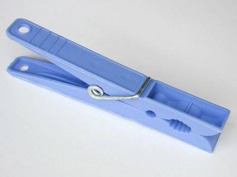 Spring-type blue plastic clothespin, symbol of household and laundry, close-up on gray