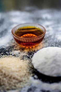 Face mask for flawless skin on wooden surface consisting of rice flour,corn flour,honey,milk, in a glass bowl and entire raw ingredients present on the surface.