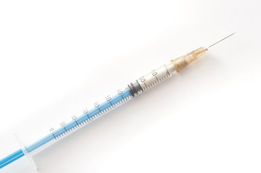 Small plastic disposable hypodermic syringe and needle for self administering drugs in a disease such as diabetes lying diagonally on white with copyspace