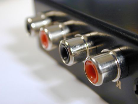 Red and black analog RCA audio phono connections on black metal panel in close-up selective focus
