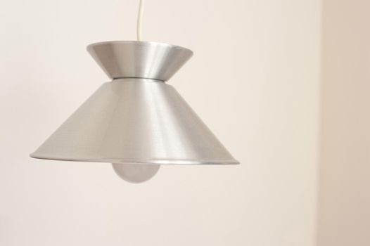 Stylish simple metal light fitting hanging from the ceiling with a shiny silver metallic finish shade and globe - switched off