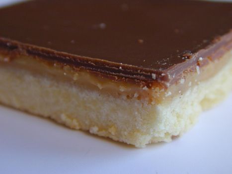 Close-up of a caramel shortcake made of rectangular shortbread biscuit base topped with caramel filling and milk chocolate topping