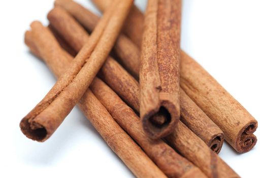 Close up detail of rolled cinnamon sticks used as a spice and condiment in cooking over a white background