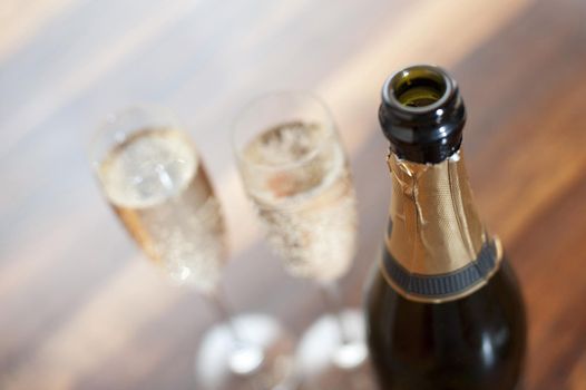 Close up of the neck of an open champagne bottle with full glasses or flutes alongside for a romantic evening or to toast a special event