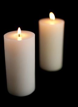 two lit christmas candles on a black background