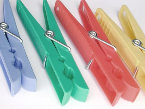 Four colorful plastic clothes pegs on a white background conceptual of housework, cleanliness and laundry