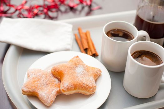 Serving of espresso coffee and freshly baked sugared Christmas doughnuts in the shape of a star for a festive Xmas coffee break