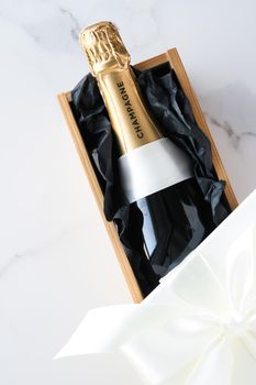 Wedding celebration, lifestyle and luxury present concept - A champagne bottle and a gift box on marble