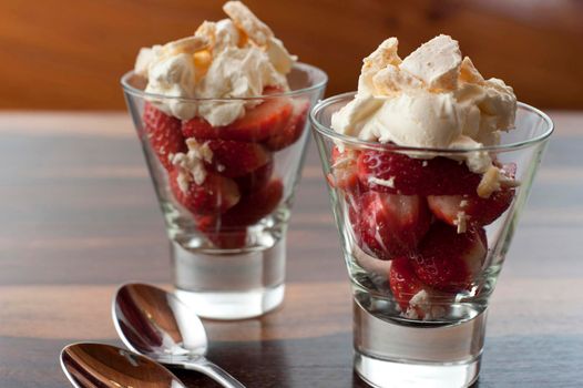 Strawberries and whipped cream dessert in two tall glasses for a delicious fruity sweet