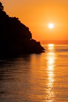 Beautiful view of orange sunset with rocks in Calabria, Mediterranean Sea, Italy. Tropical colorful sunrise landscape. Seascape