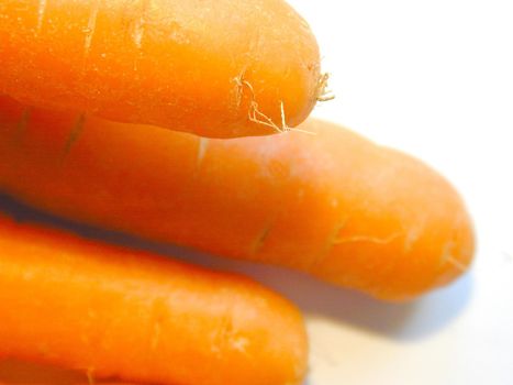 Close up texture of fresh raw carrots on a white background with focus to a single carrot in the top right of the frame