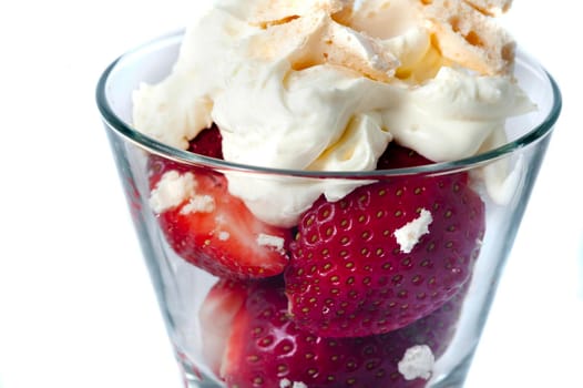 Ripe fresh strawberries served with whipped cream in a tall dessert glass, close up view isolated on white