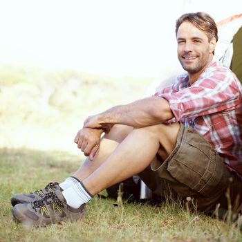 Letting nature surround him. Portrait of a handsome young man sitting at the entrance to his tent