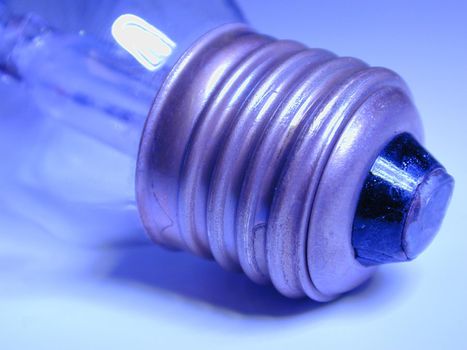 Screw fitting on an electric light bulb viewed close up on the threads in blue light in a power and energy concept