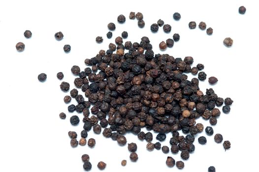 Black peppercorns, the dried berries of the Piper nigrum plant, used as a spice and seasoning in cooking on a white background