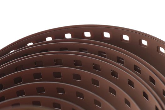 Close up detail of a roll of 35mm film viewed from a high angle showing the coils of the reel and sprockets , isolated on white