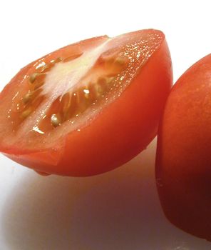 Fresh halved juicy red tomato dripping juice ready to be used in a healthy salad or as a cooking ingredient in a recipe