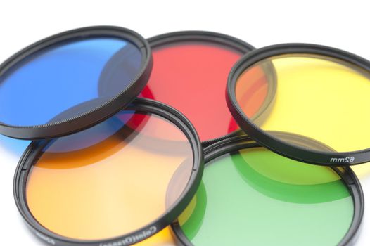 Close up of five round camera lens contrast filters in colors of blue, red, orange, green and yellow