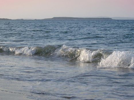 waves breaking on a shore at sunset