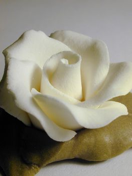 Yellow icing sugar rose to decorate a cake, close up view on grey