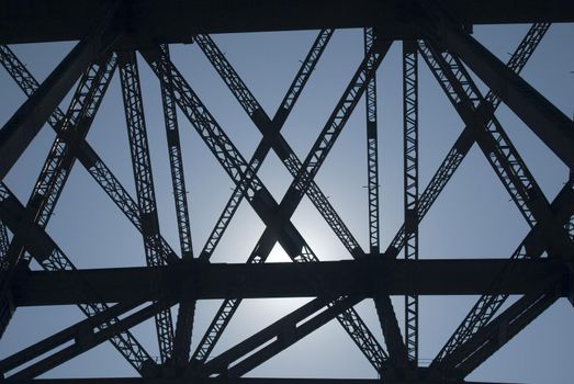 Lattice work of bridge girders silhouetted against the sun in a structural engineering concept