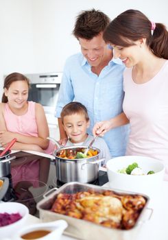 An enthusiastic family in the kitchen. A happy family cooking a large, delicious meal together in the kitchen