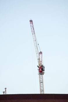 Top of a construction crane colored white and red viewed from low angle against clear blue sky