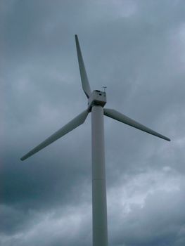 Wind turbine blades and generator against a cloudy sky supplying sustainable energy from the coversion of kinetic wind energy to electricity