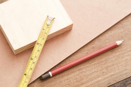 Carpentry background with samples of three different woods, a pencil and builders tape measure marked in centimetres and inches