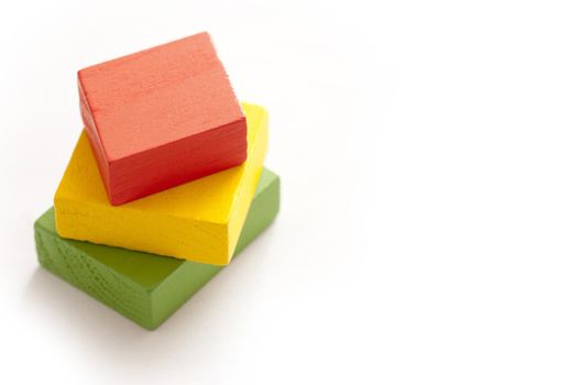 Single stack of red, yellow and green painted blocks for babies over white background with copy space