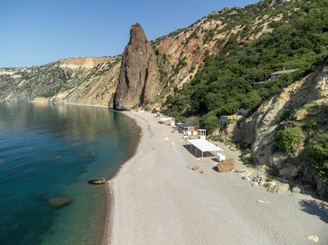Sea landscape with rocky coastline on sunset time with cloudy sky. Yachts in the Sea on a background of rocky shores. The concept of perfect place for summer travel and rest.