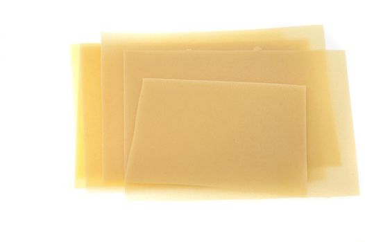 Dried sheets of uncooked Italian lasagne pasta made from durum wheat on a white background