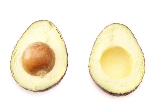 Halved fresh tropical avocado pear viewed from above with the pip still in for a delicious healthy nutrient rich salad ingredient, isolated on white