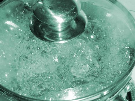 Boiling pot of water on a stove with a glass lid so that the bubbles are visible