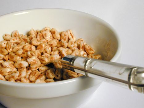 Close up view looking down the handle of the spoon into a plate of breakfast cereal for a healthy start to the day