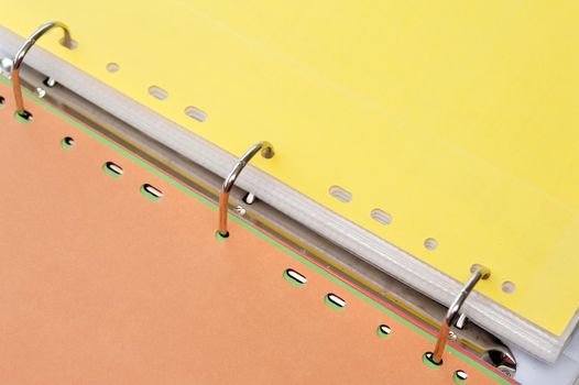 Three ring binder open to the center between yellow and brown tabbed dividers