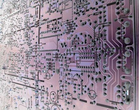 Abstract close up of the circuitry within a large, complex purple electronic motherboard.