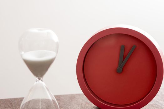 Deadline or countdown concept with egg timer or hour glass and colorful red modern clock in a close up view