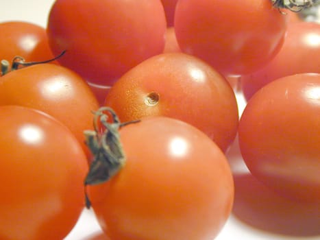 Fresh uncooked ripe red cherry tomatoes, close up background view with focus to one in the centre of the frame