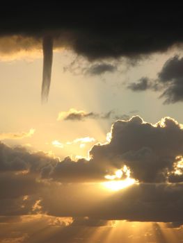 A cold air funnel dropping from the base of a dark storm cloud