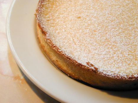 Freshly baked golden crispy pastry pie crust sprinkled with icing sugar served on a plate in a close up culinary or baking background