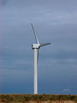 Alternative wind energy with a tall aeolian or wind turbine on a hilltop which converts the kinetic energy of the wind to electrical energy