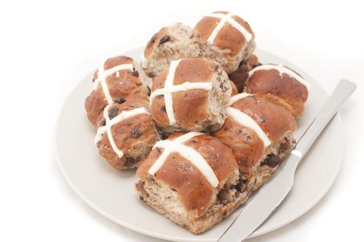 Plate of freshly baked spicy fruity Hot Cross Buns with raisins symbolic of the crucifixion of Christ at Easter