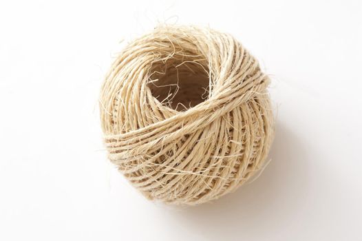 Ball of twine made from natural hemp fibers viewed high angle on white