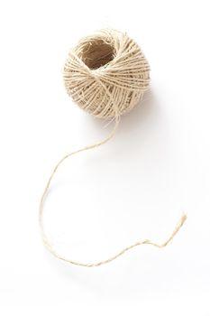 Ball of household string or twine made from hemp fibres on a white background, high angle