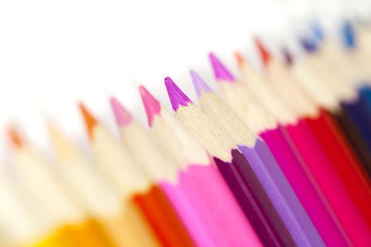Extreme macro selective focus close up view on warm tones of colored pencils over white background